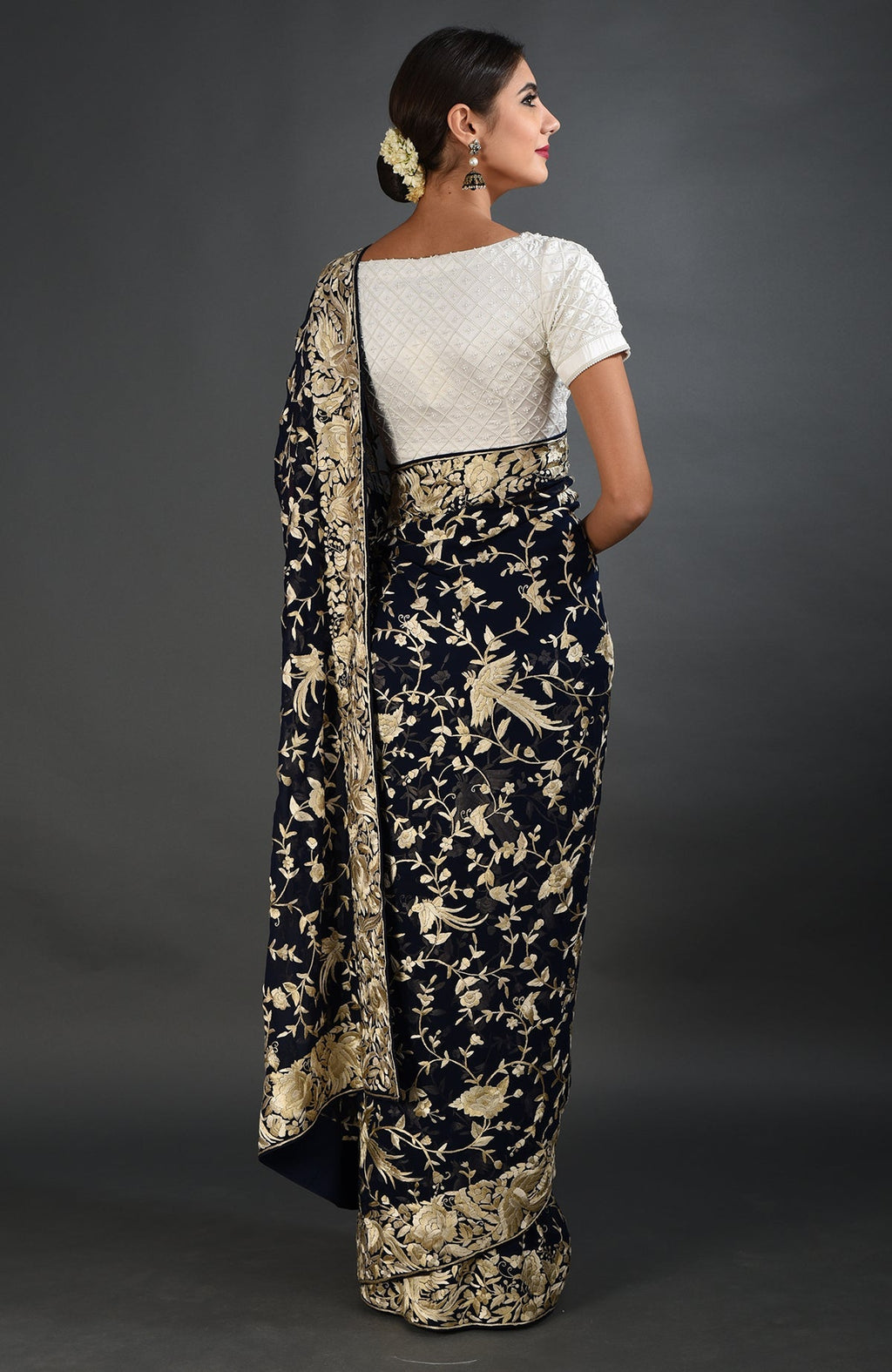 A woman models a midnight blue Parsi Gara hand-embroidered saree with a white blouse.