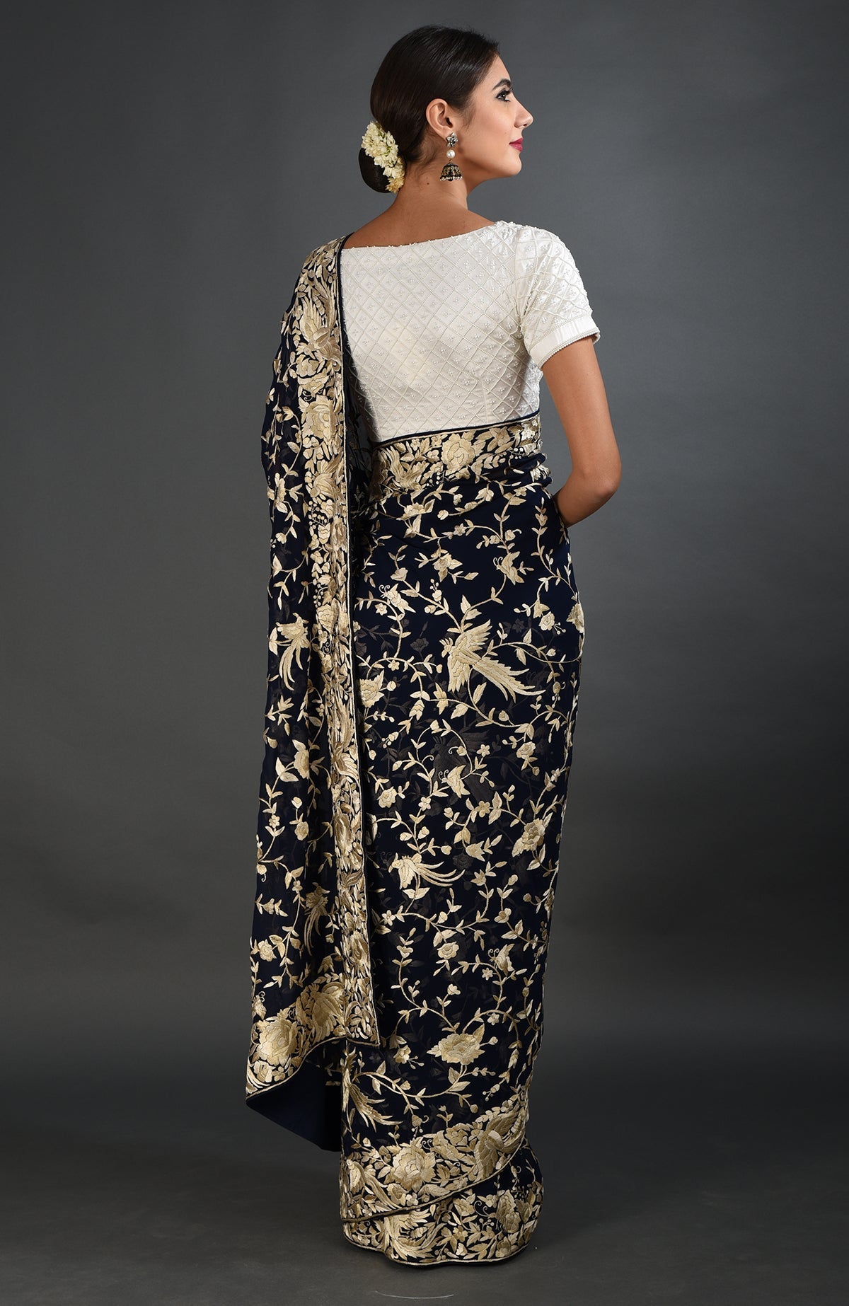 A woman models a midnight blue Parsi Gara hand-embroidered saree with a white blouse.