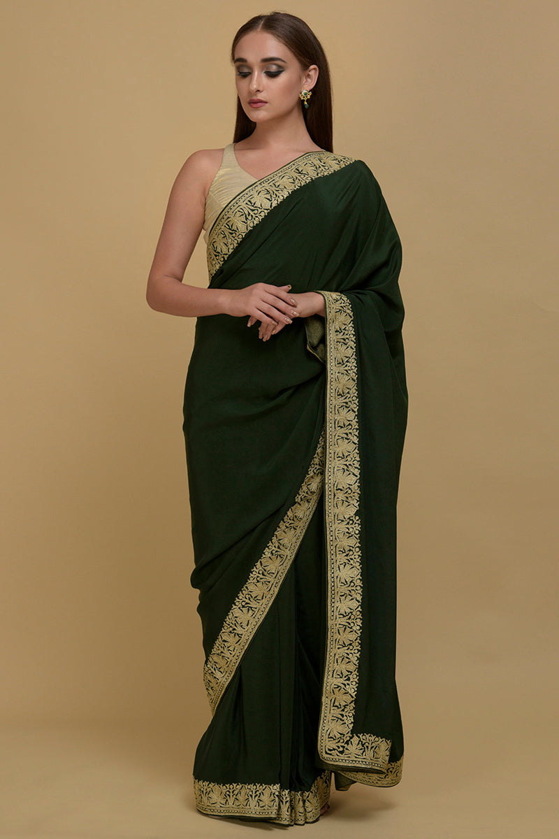 Bottle green pure crepe saree with gold tilla aari embroidered borders.