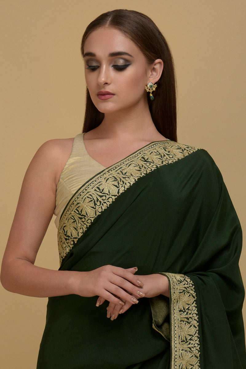 Bottle green pure crepe saree with gold tilla aari embroidered borders.