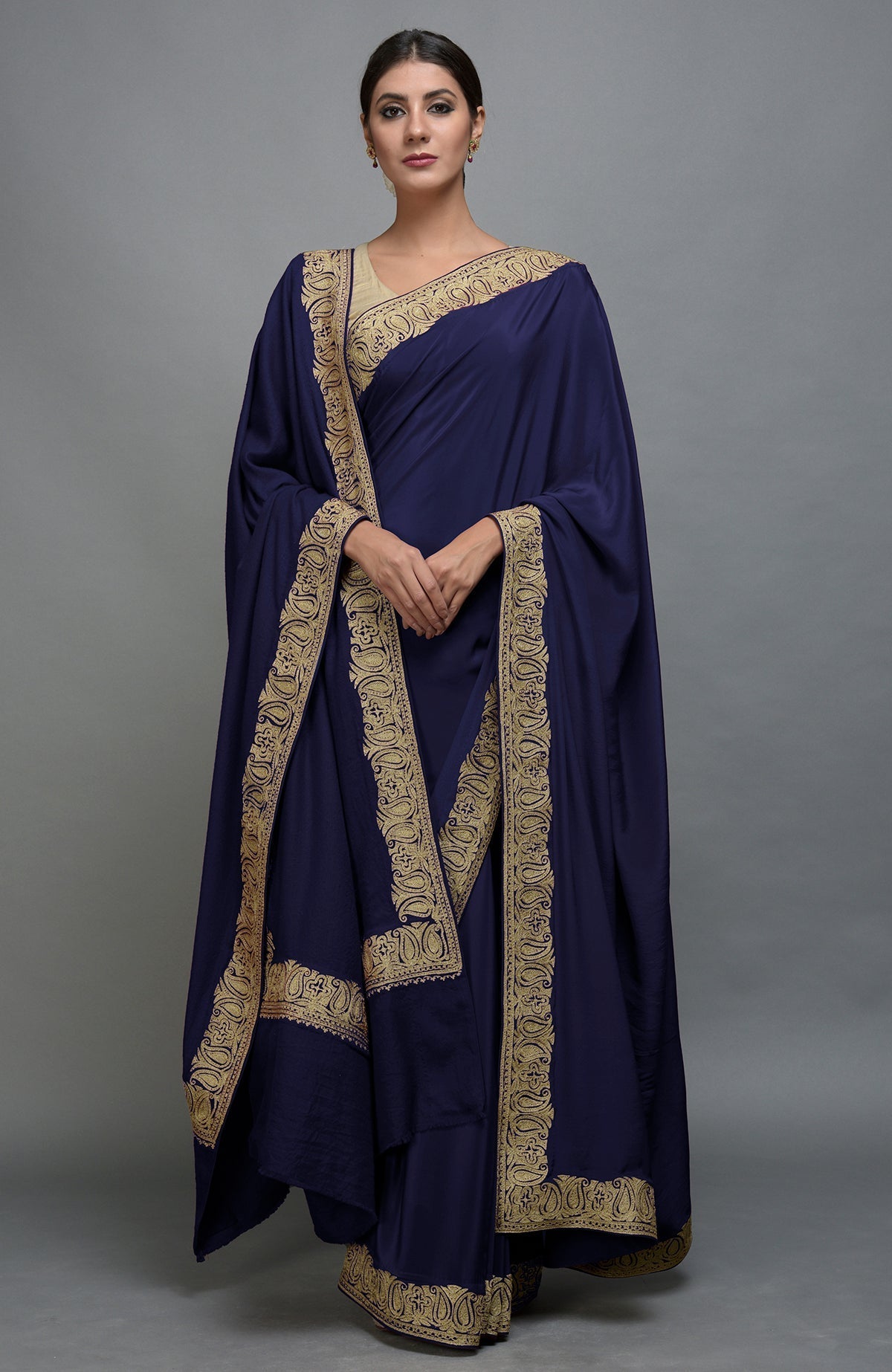 A woman models a navy blue saree and pashmina shawl set with gold paisley embroidery.