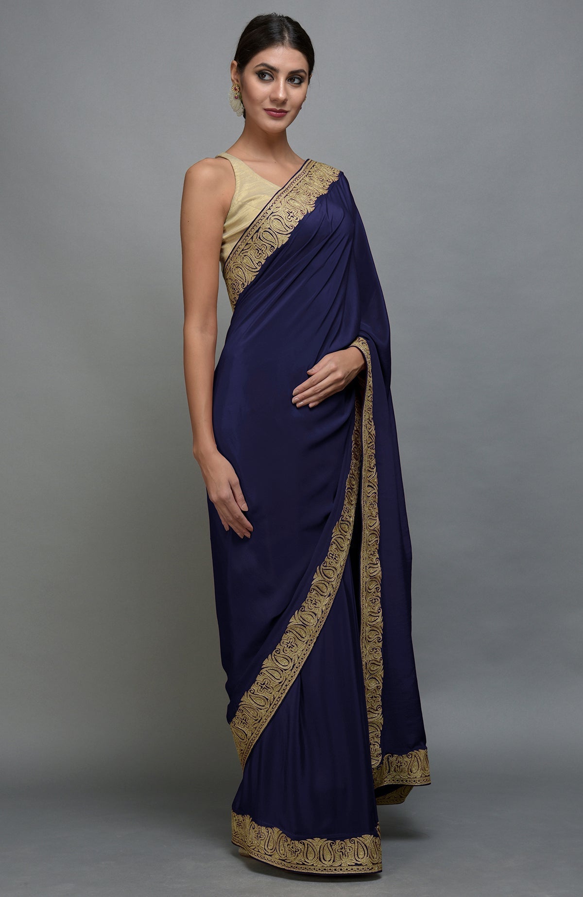 A woman models a navy blue pure crepe saree with gold paisley embroidered borders.