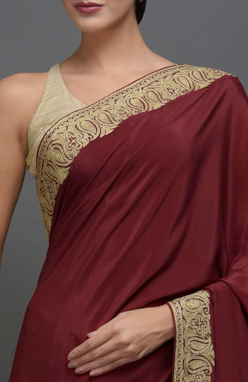 Maroon pure crepe saree with gold paisley tilla aari embroidery on the borders.