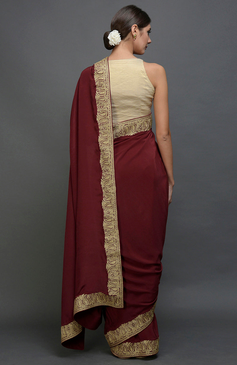 Maroon pure crepe saree with gold paisley tilla aari embroidered borders.