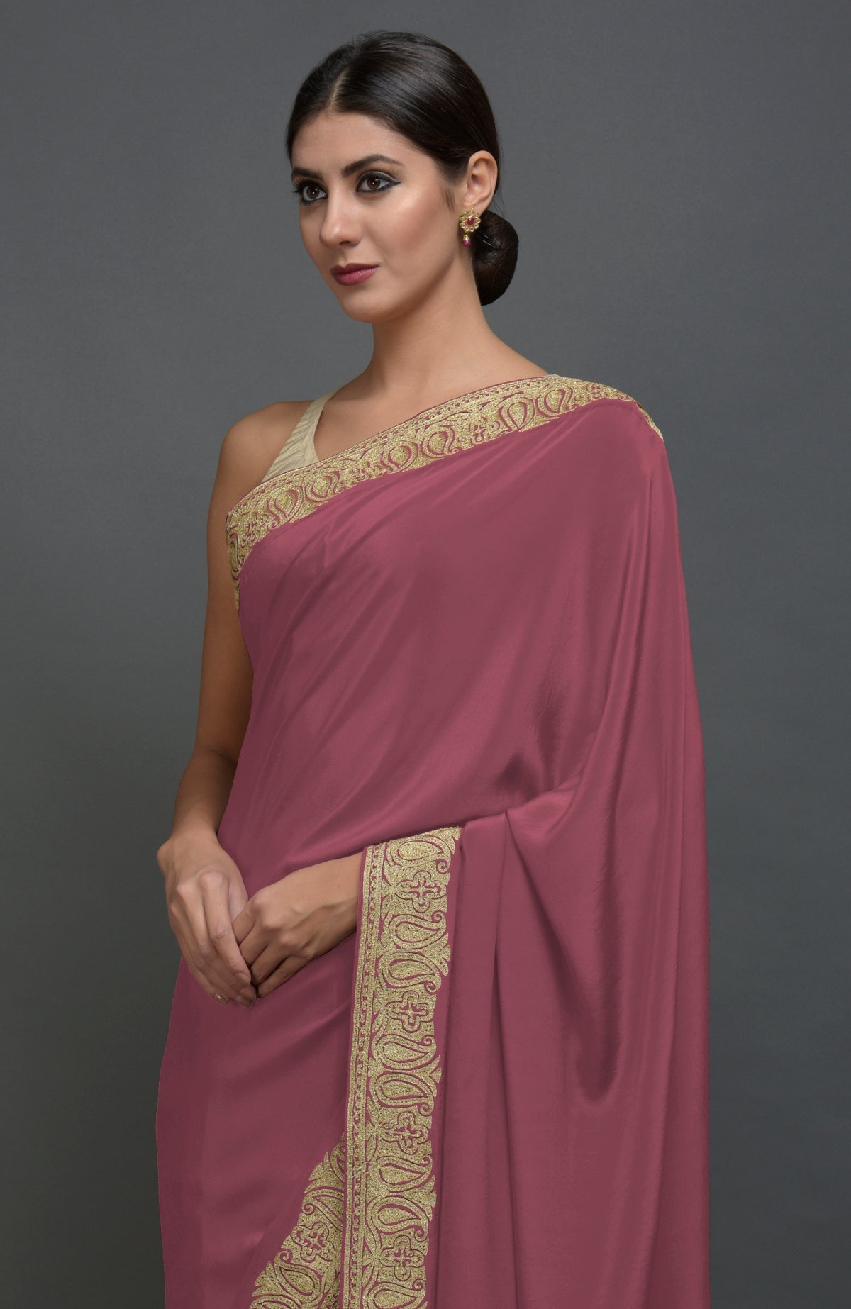 A woman models a China rose pure crepe saree with gold tilla aari embroidery.