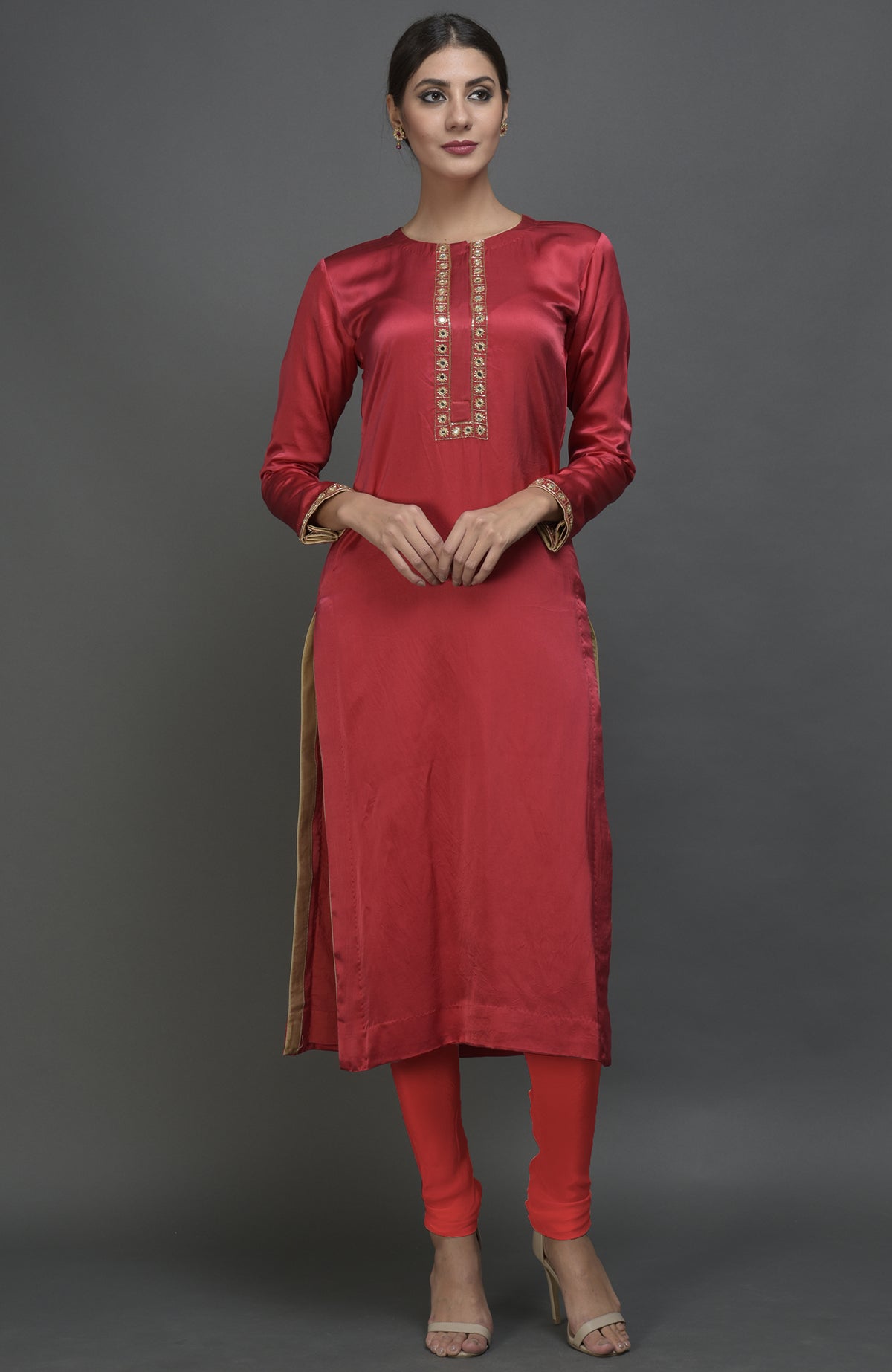 A woman models a red satin silk suit with mirror and zardozi embroidery.