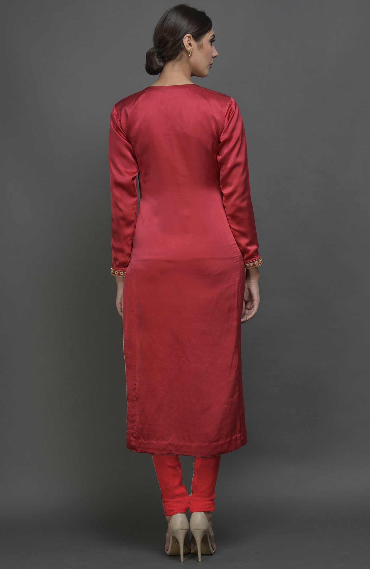 A woman from behind wears a red satin silk suit with embroidered sleeves and matching pants.
