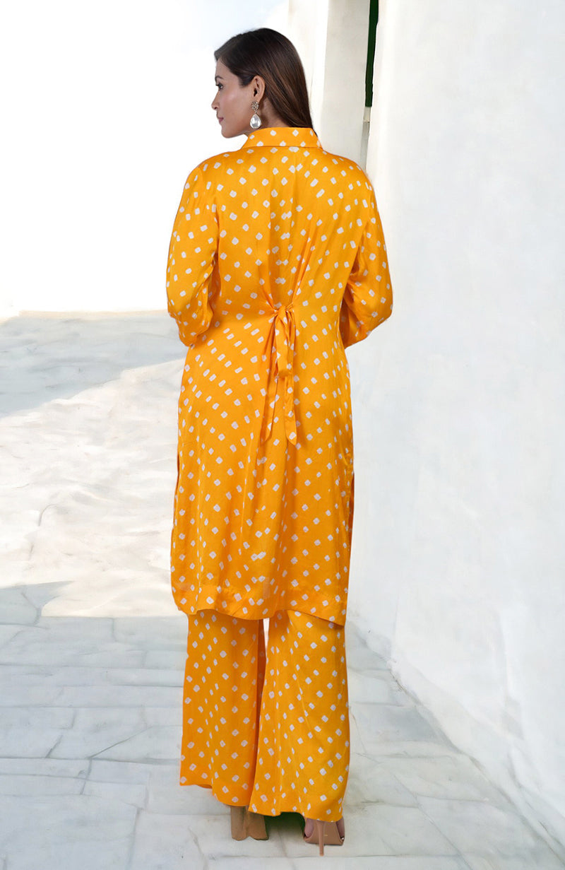 A woman models a turmeric yellow bandhej embroidered co-ord set with matching pants.