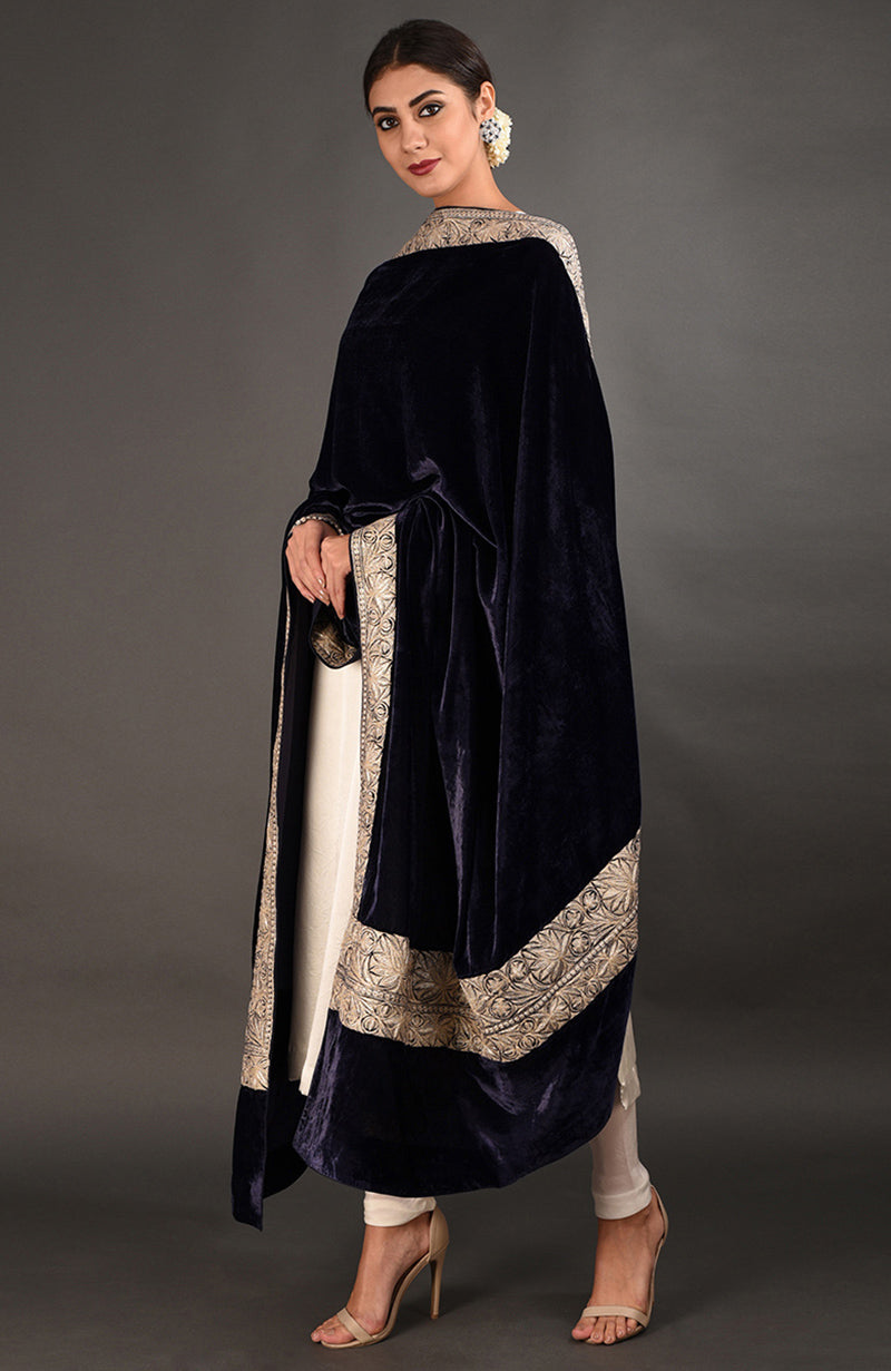 A woman models a midnight blue velvet shawl with intricate gold embroidery.