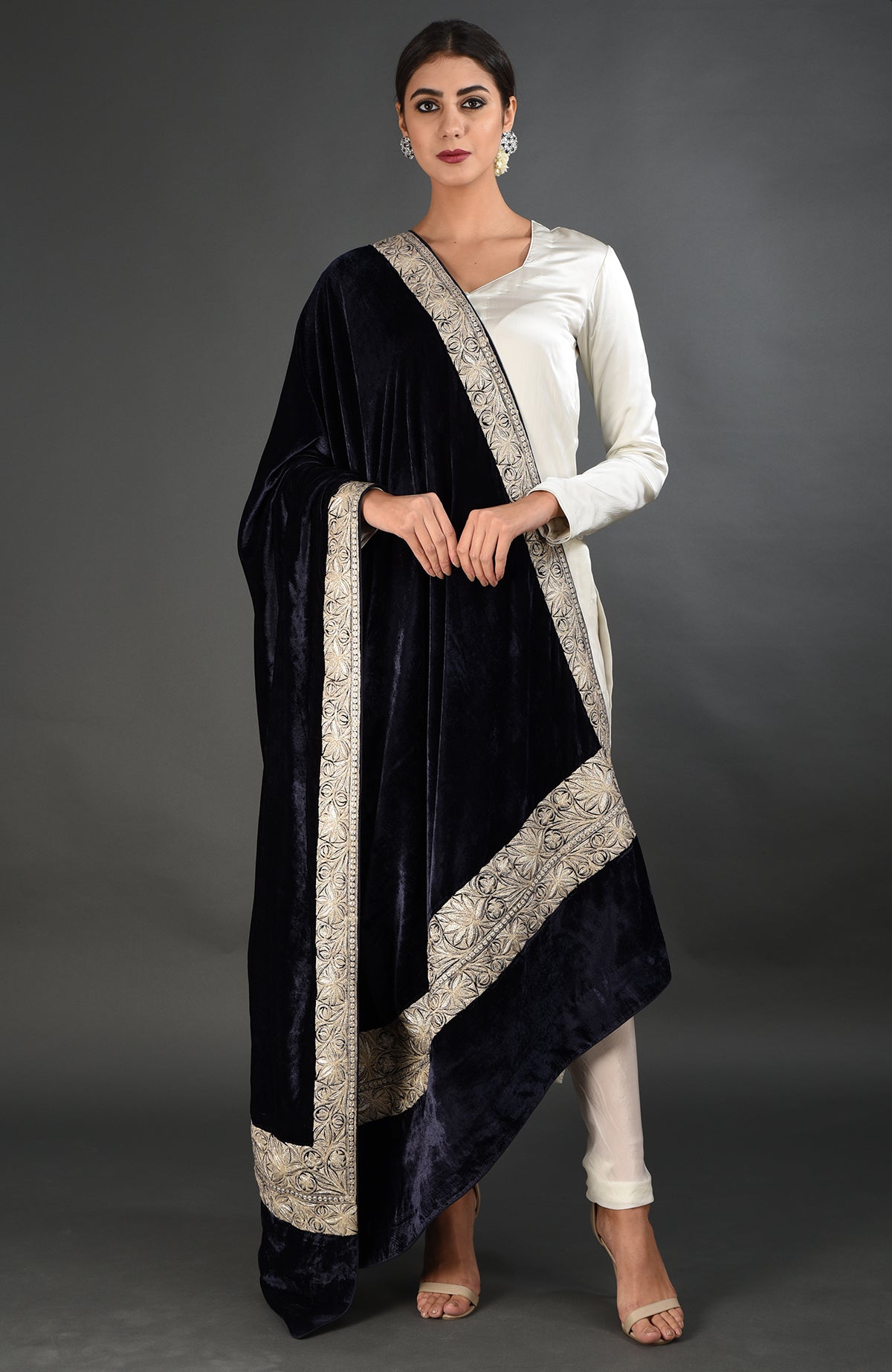 A woman models a midnight blue velvet dupatta with silver tilla embroidery over a white suit.
