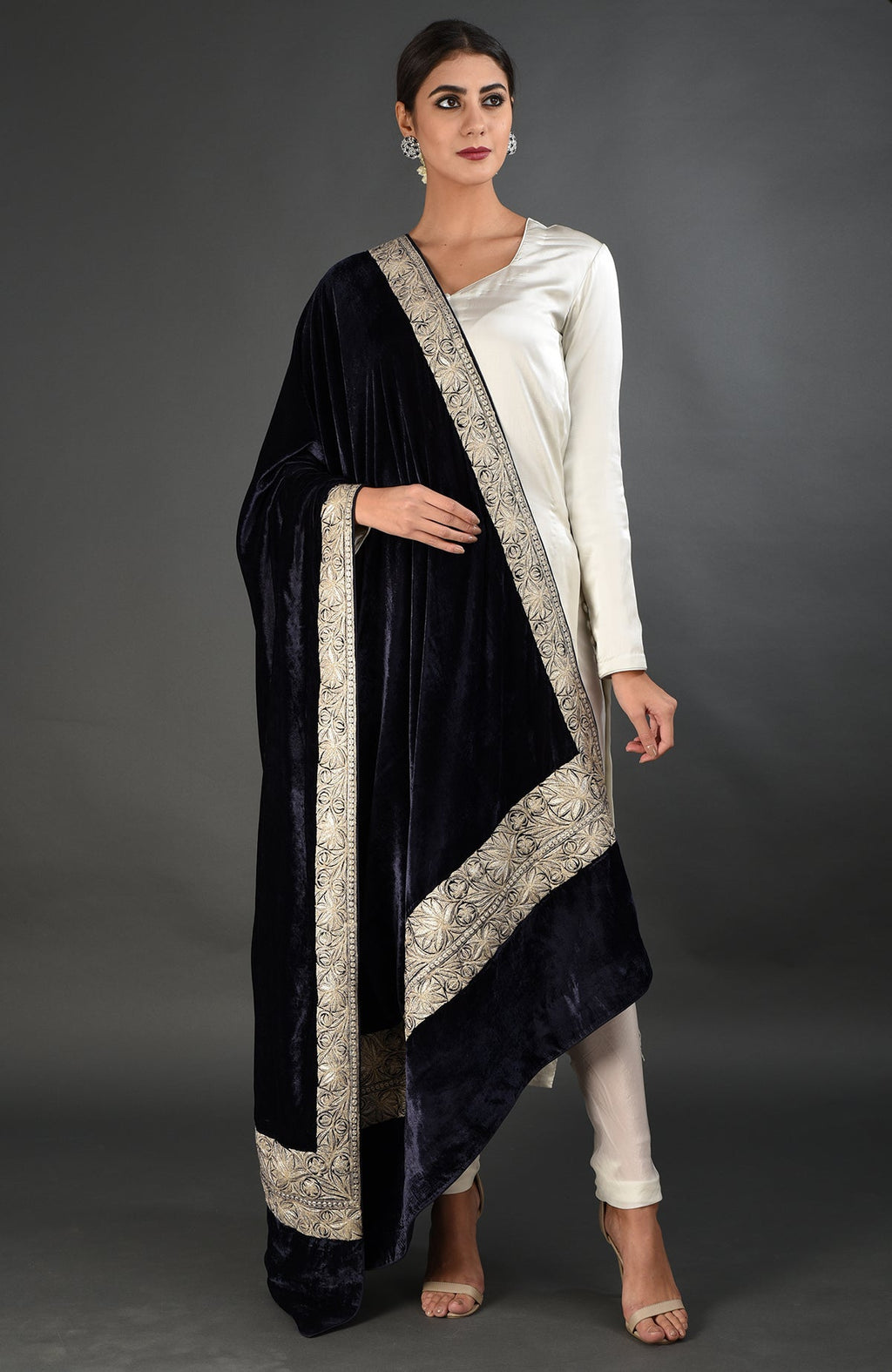 A woman models a midnight blue velvet dupatta with silver tilla embroidery over a white suit.