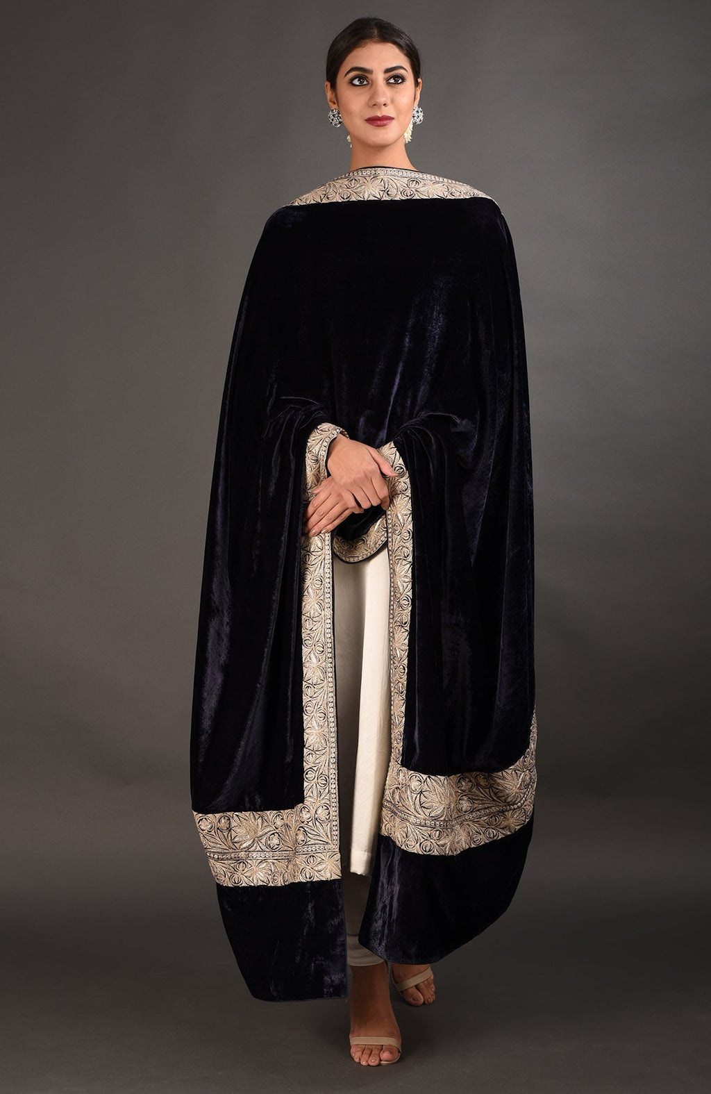 A woman models a midnight blue velvet dupatta with intricate silver embroidery over a white suit.