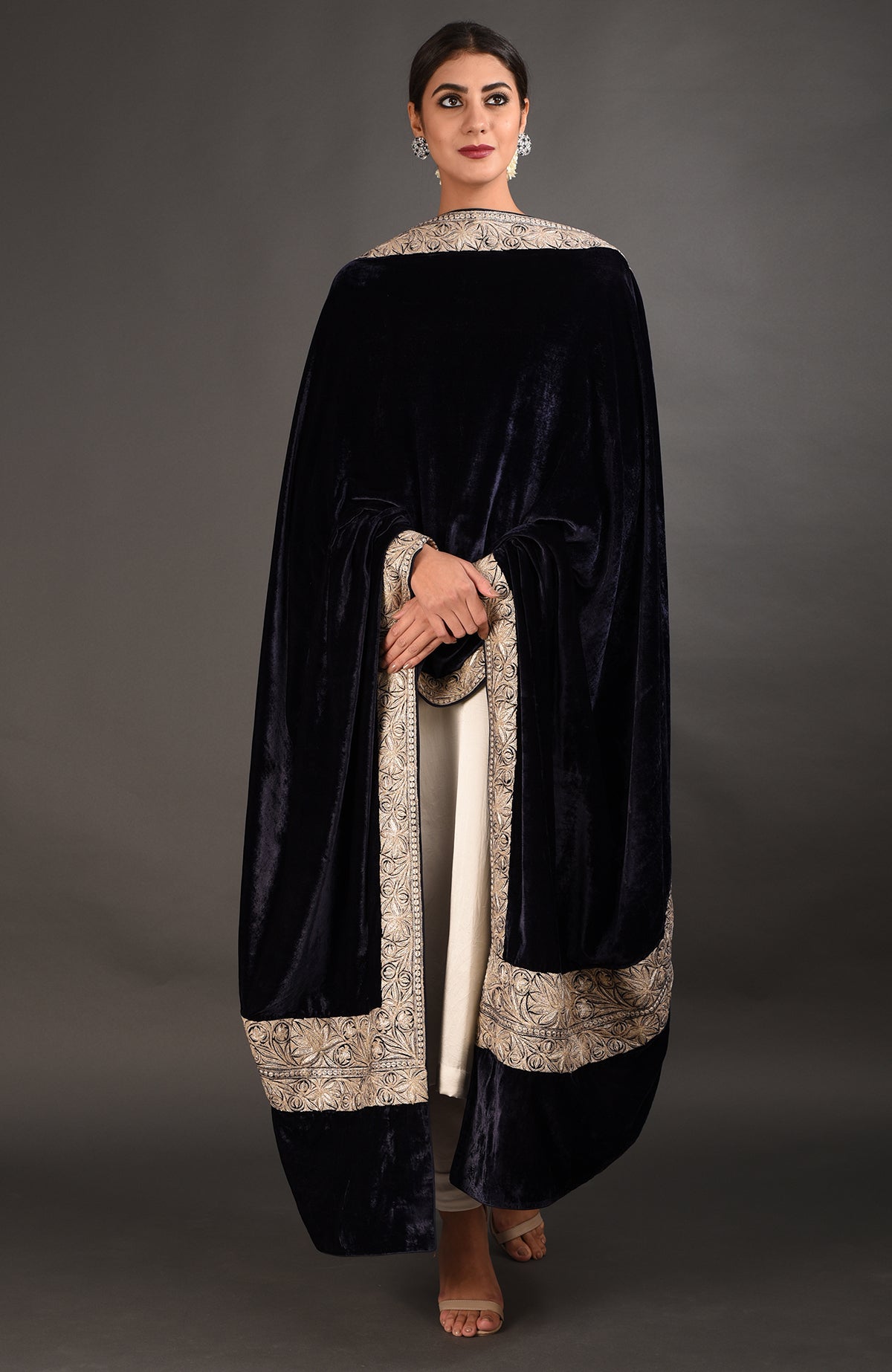 A woman models a midnight blue velvet dupatta with intricate silver embroidery over a white suit.