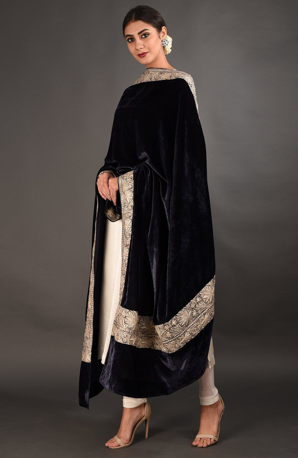 A woman models a midnight blue velvet dupatta with silver tilla embroidery over a white suit.