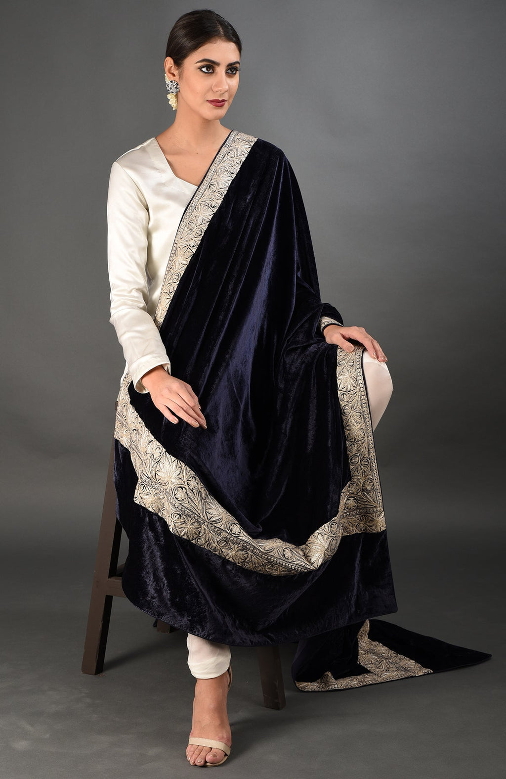 A woman models a midnight blue velvet dupatta with silver tilla embroidery over a white suit.