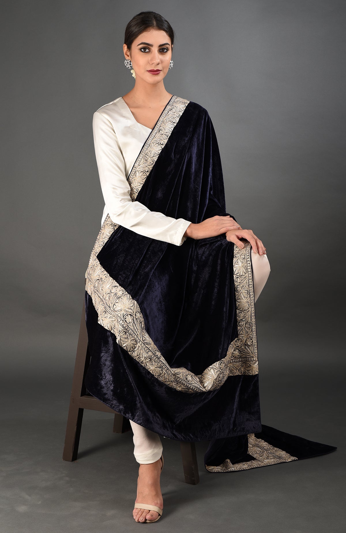 A woman models a midnight blue velvet dupatta with silver tilla embroidery and a white suit.
