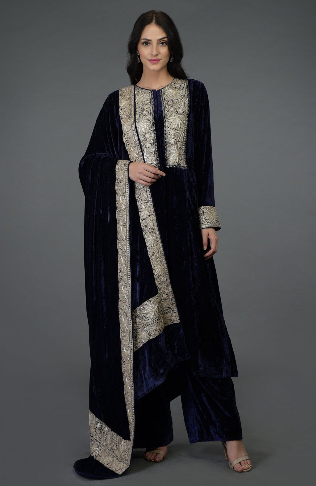 A woman models a midnight blue velvet suit with silver Kashmiri Tilla embroidery.