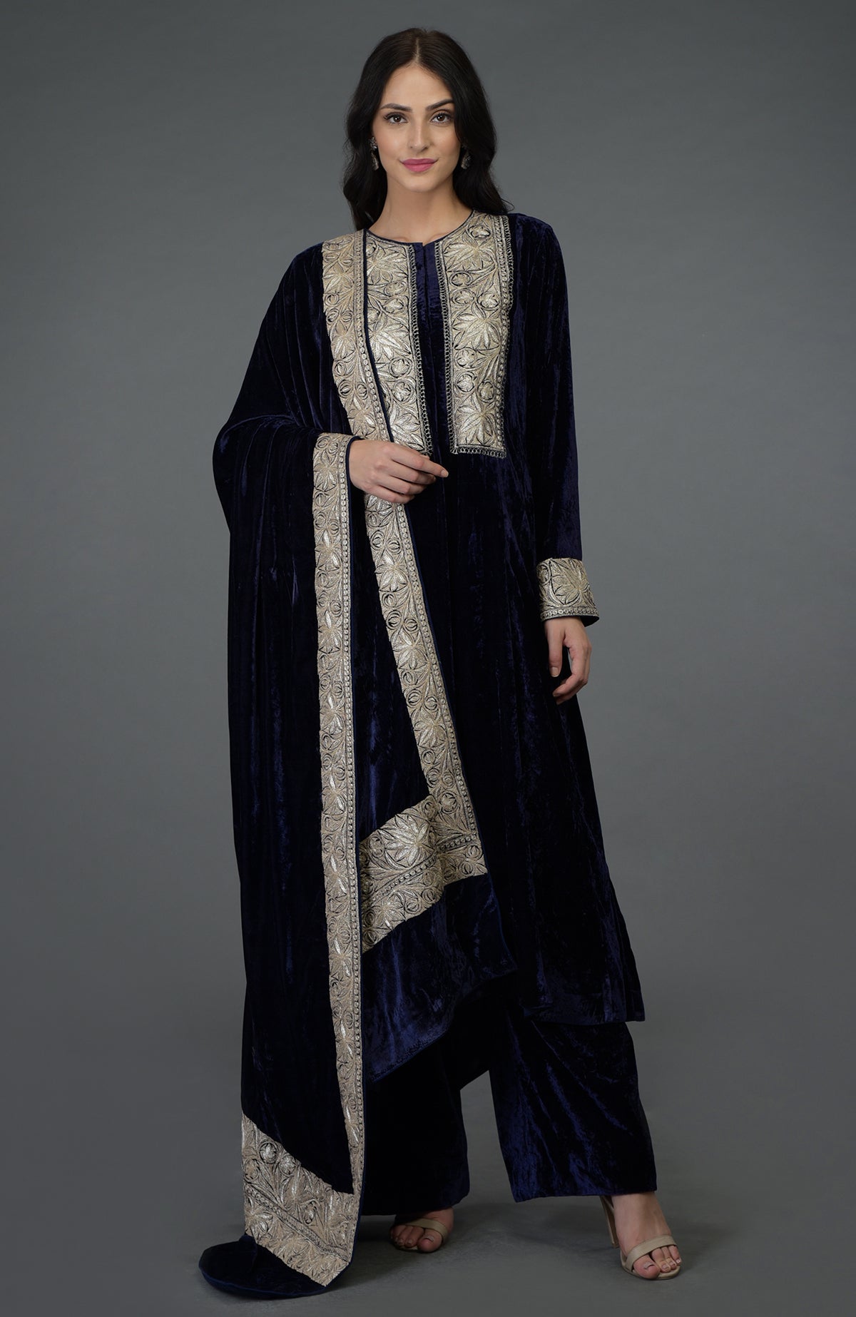 A woman models a midnight blue velvet suit with silver Kashmiri Tilla embroidery.