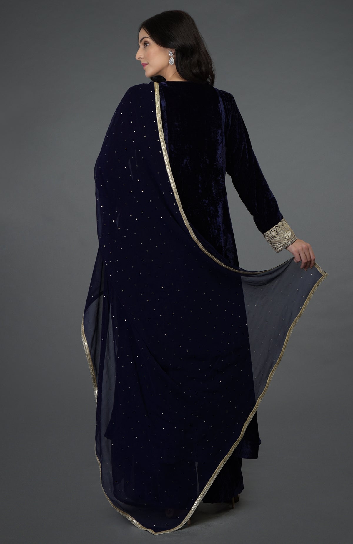 A woman models a midnight blue velvet suit with a sheer, embellished dupatta.