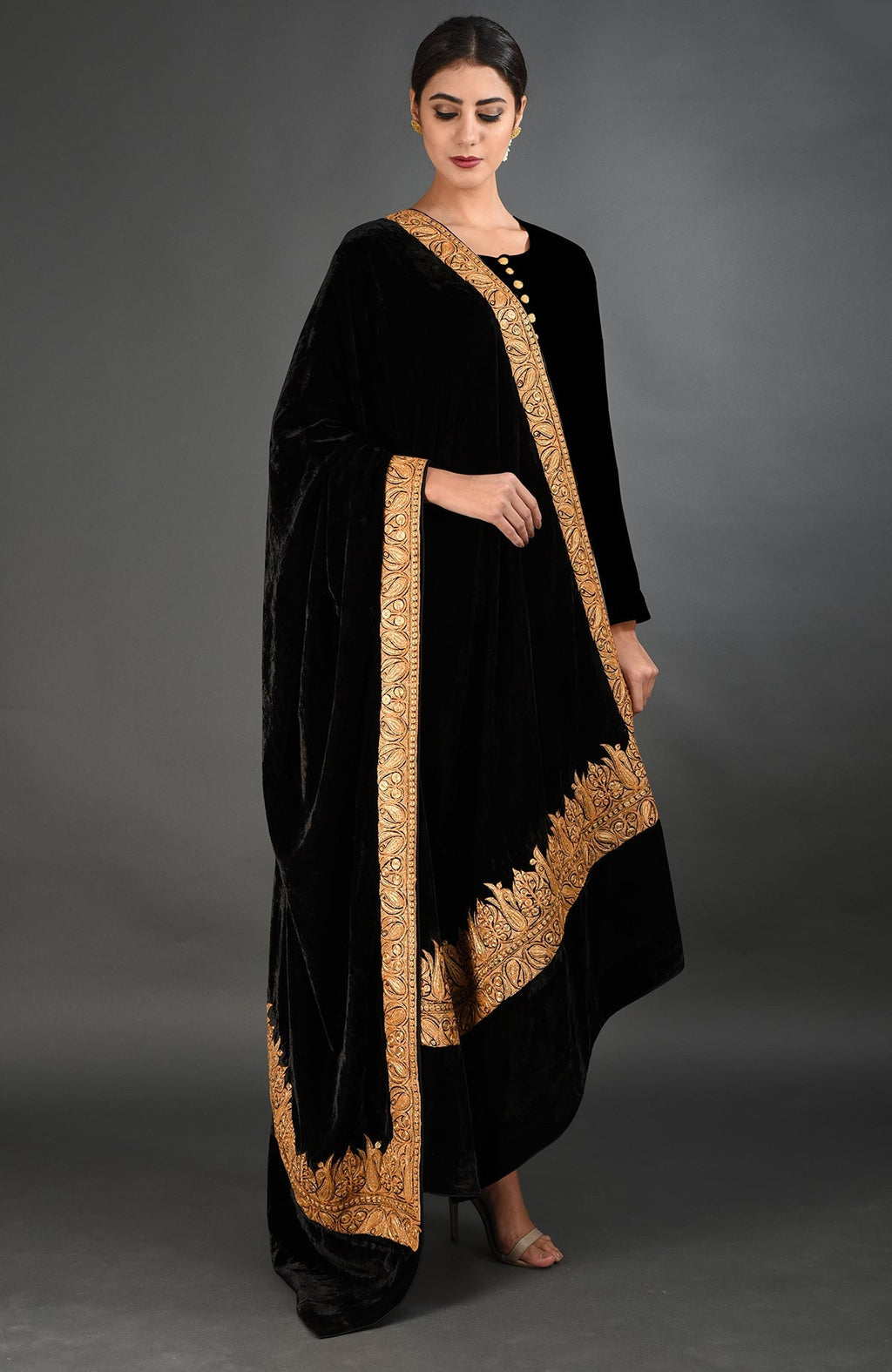 A woman models a black velvet shawl with gold Kashmiri Tilla embroidery.