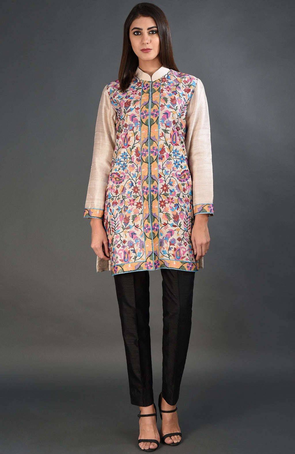 Creamy beige jacket with colorful floral embroidery, paired with black pants and heels.