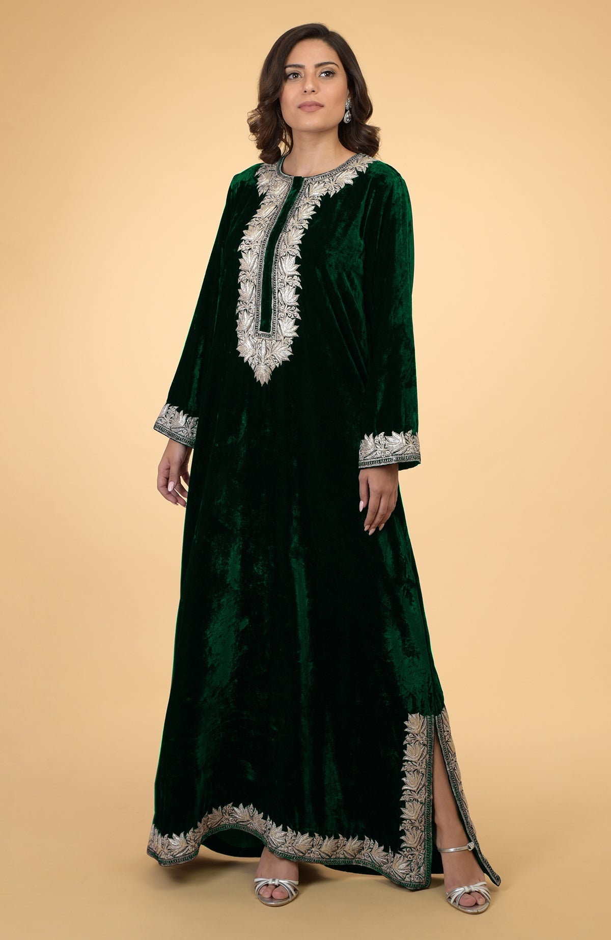 A woman models a dark green velvet kaftan with silver Kashmir embroidery.