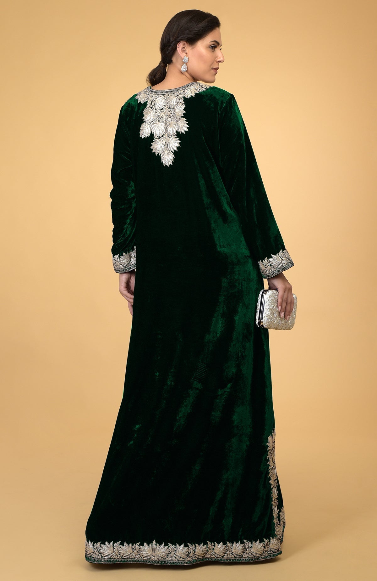 Emerald green velvet kaftan with silver Kashmir embroidery, held by a woman from behind.