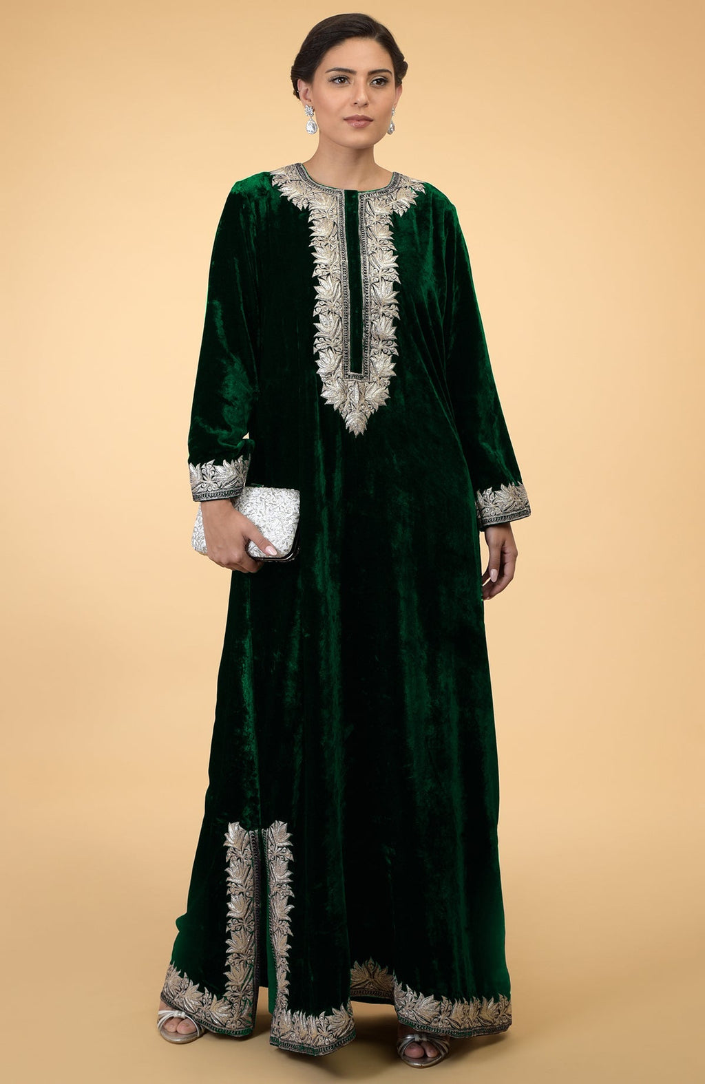 Emerald green velvet kaftan with silver Kashmir embroidery, worn by a woman holding a clutch.