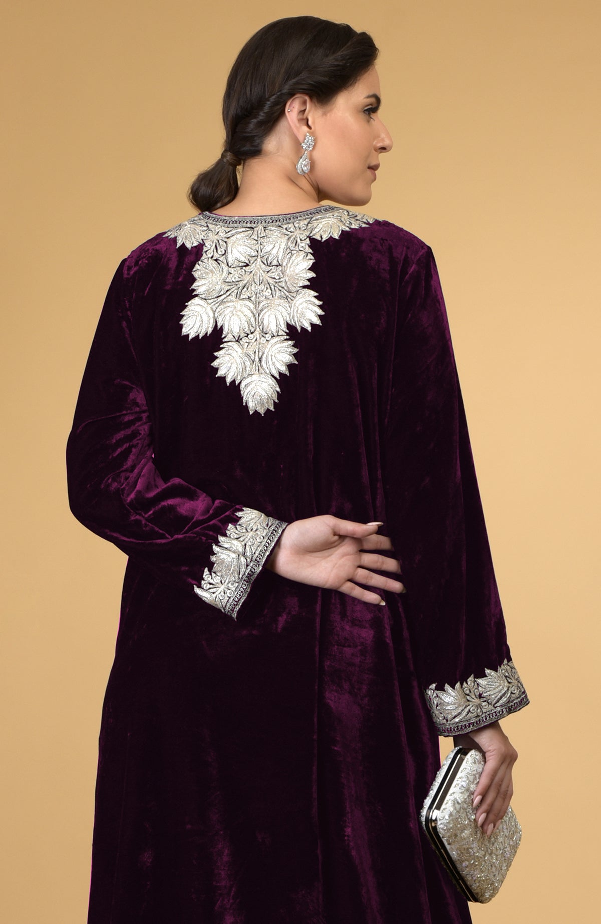 Plum velvet kaftan with silver Kashmir embroidery, worn by a model holding a clutch.