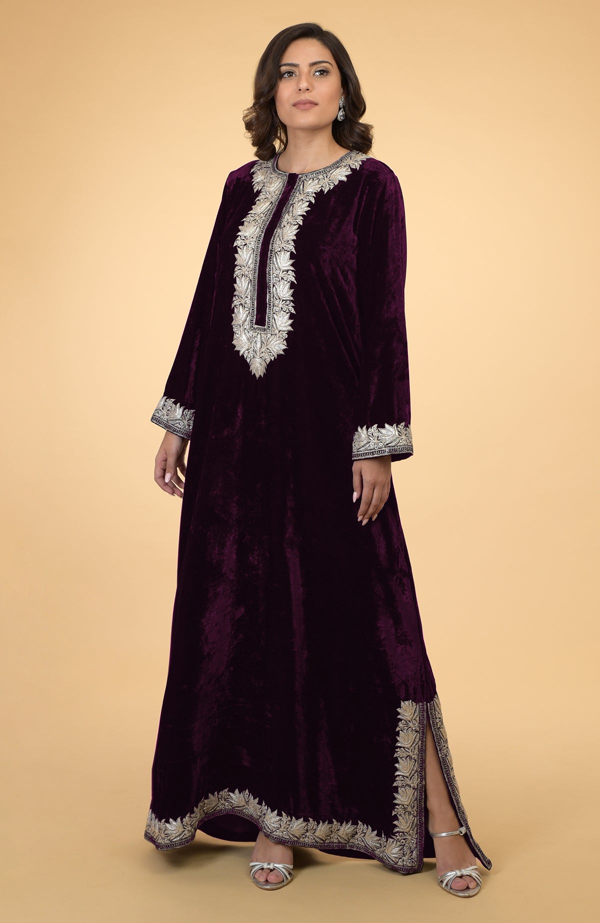 A woman models an emerald green velvet kaftan with silver Kashmir embroidery.