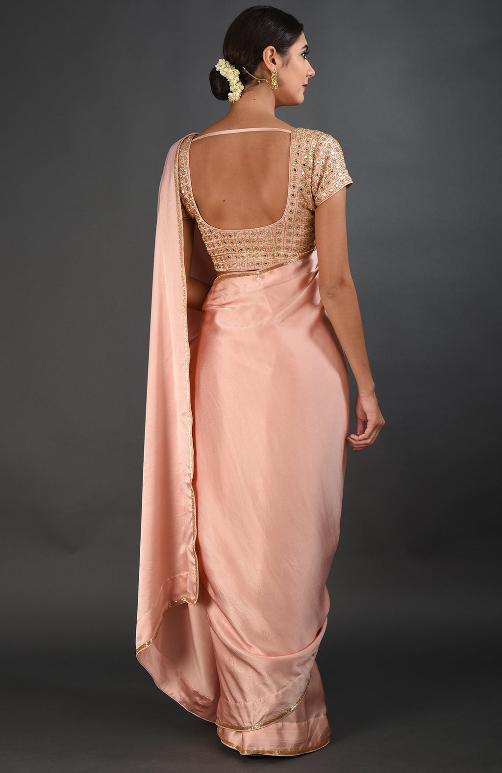 A woman models a pearl pink mirror work and zardozi hand embroidered saree.