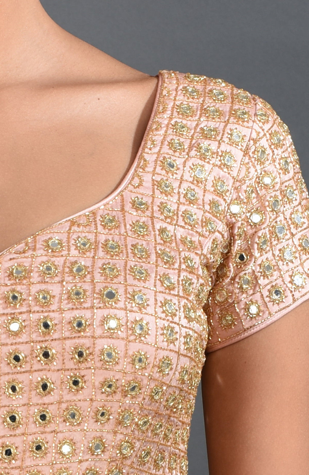 Close-up of a pearl pink blouse with mirror work and zardozi embroidery.