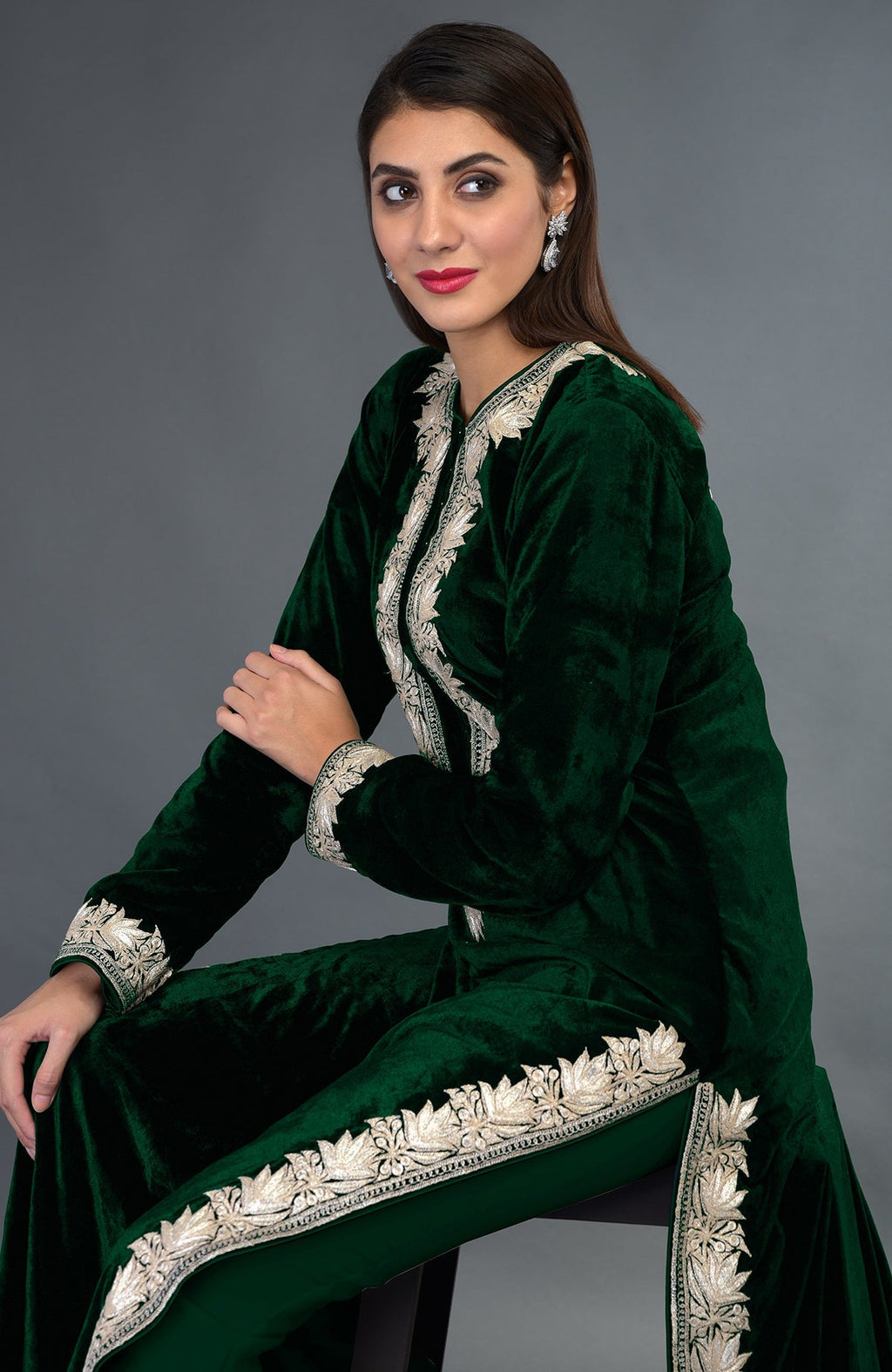 A woman models an emerald green velvet suit with silver tilla embroidery.