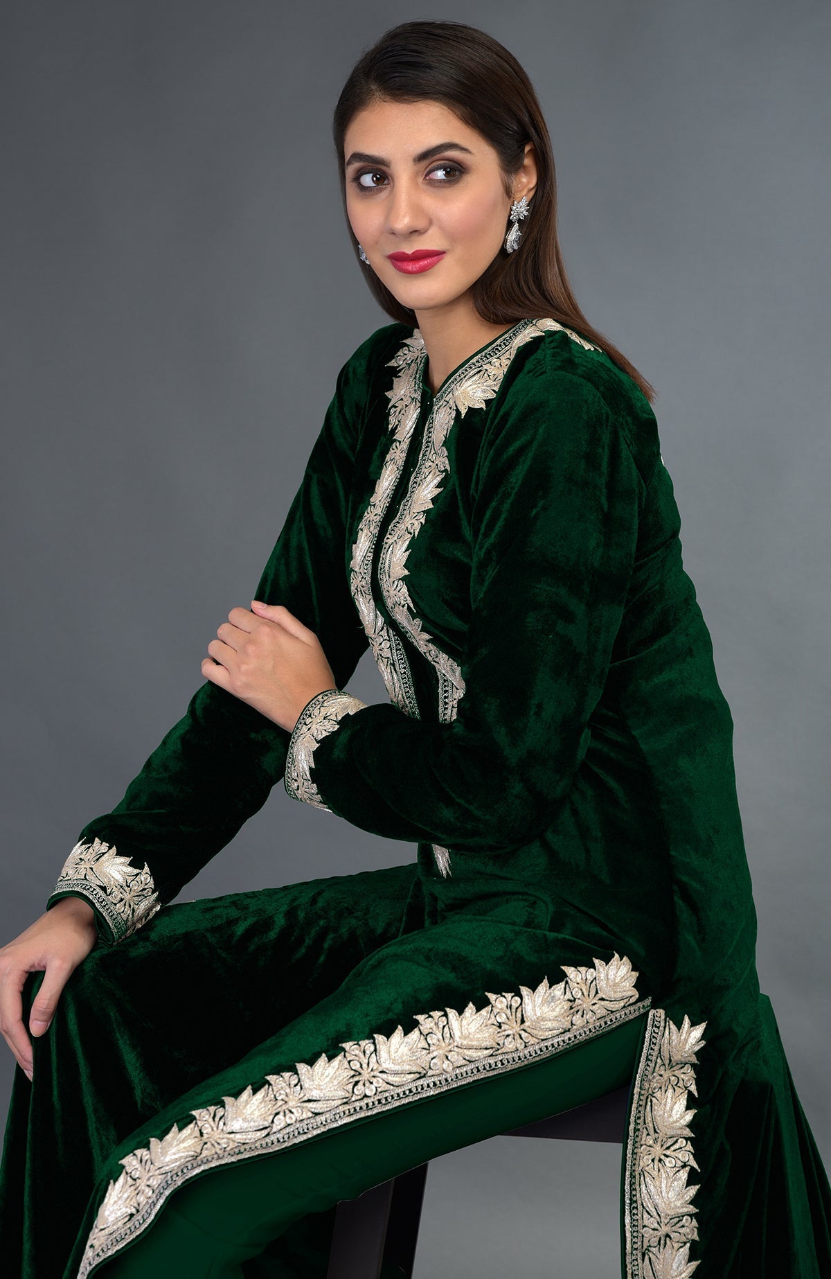 A woman models an emerald green velvet suit with silver tilla embroidery.