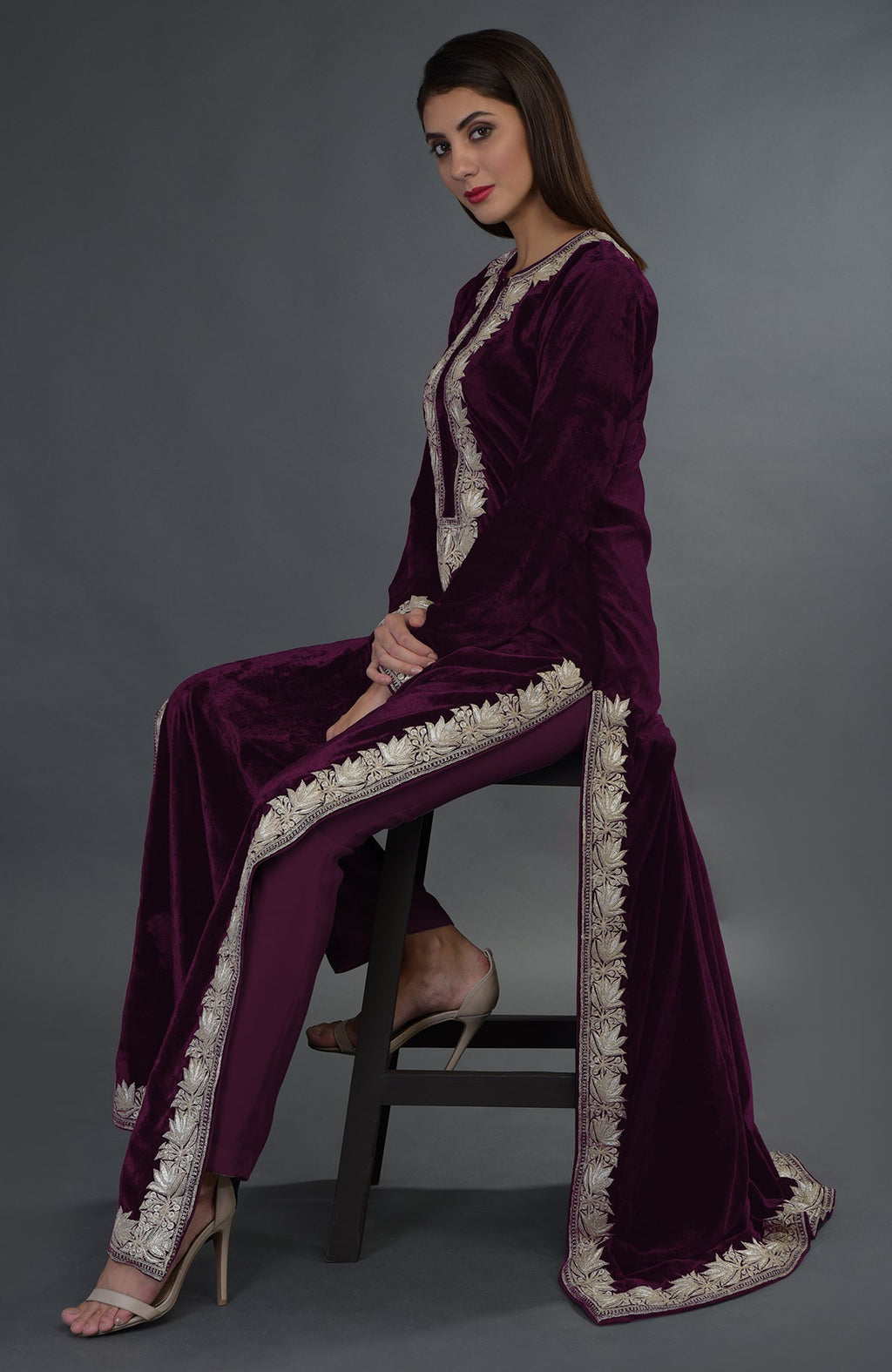A woman models a plum velvet suit with silver tilla embroidery.