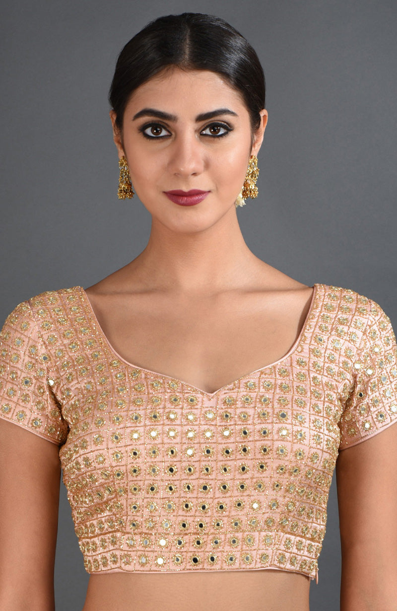 A woman models a pearl pink blouse with mirror and zardozi embroidery.