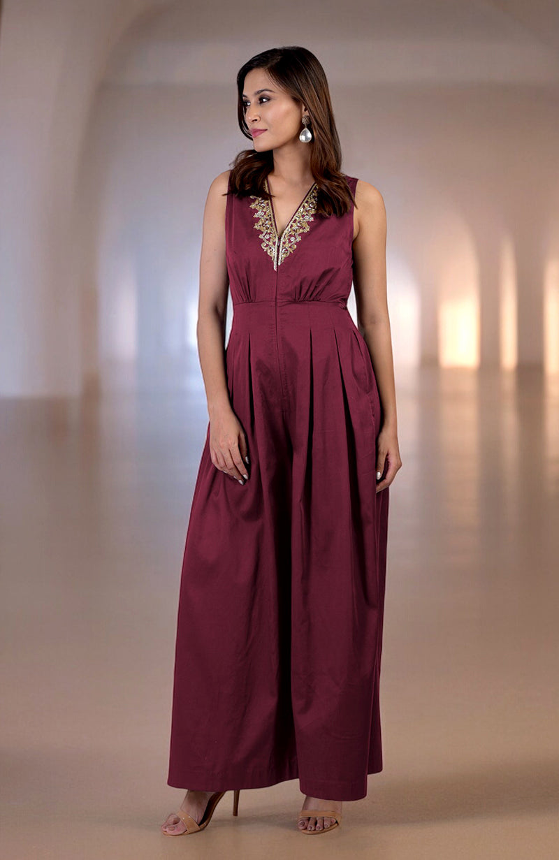 Red plum jumpsuit with gold tilla hand embroidery, V-neck, and front pleats.
