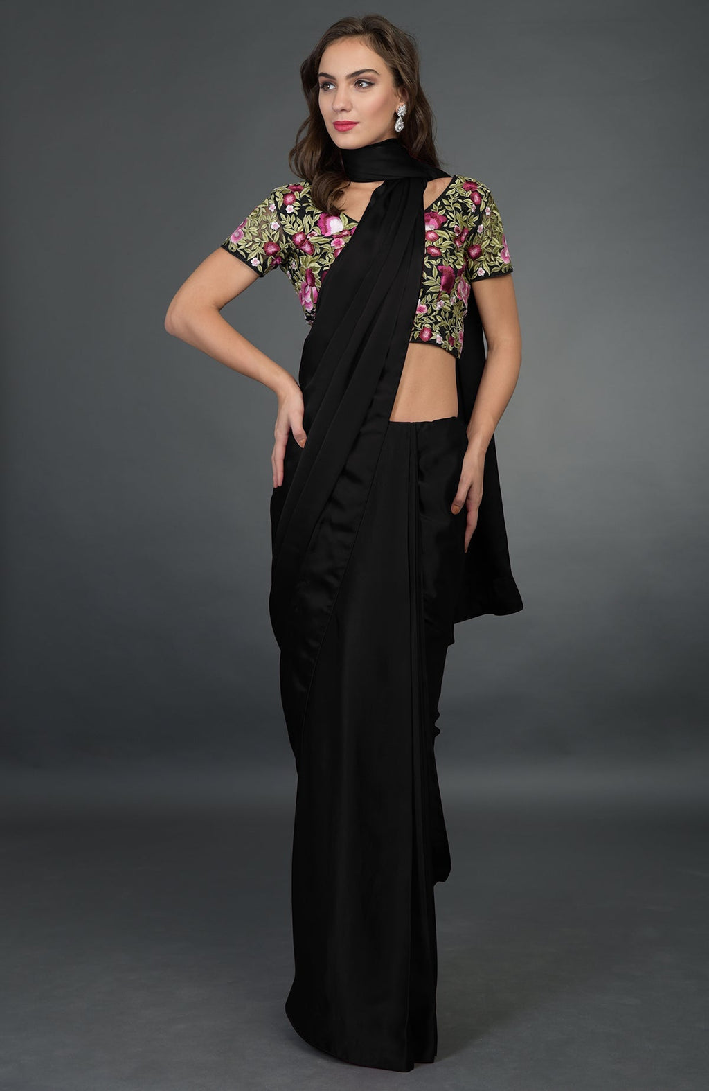 A woman models a black satin silk saree with a floral embroidered blouse.