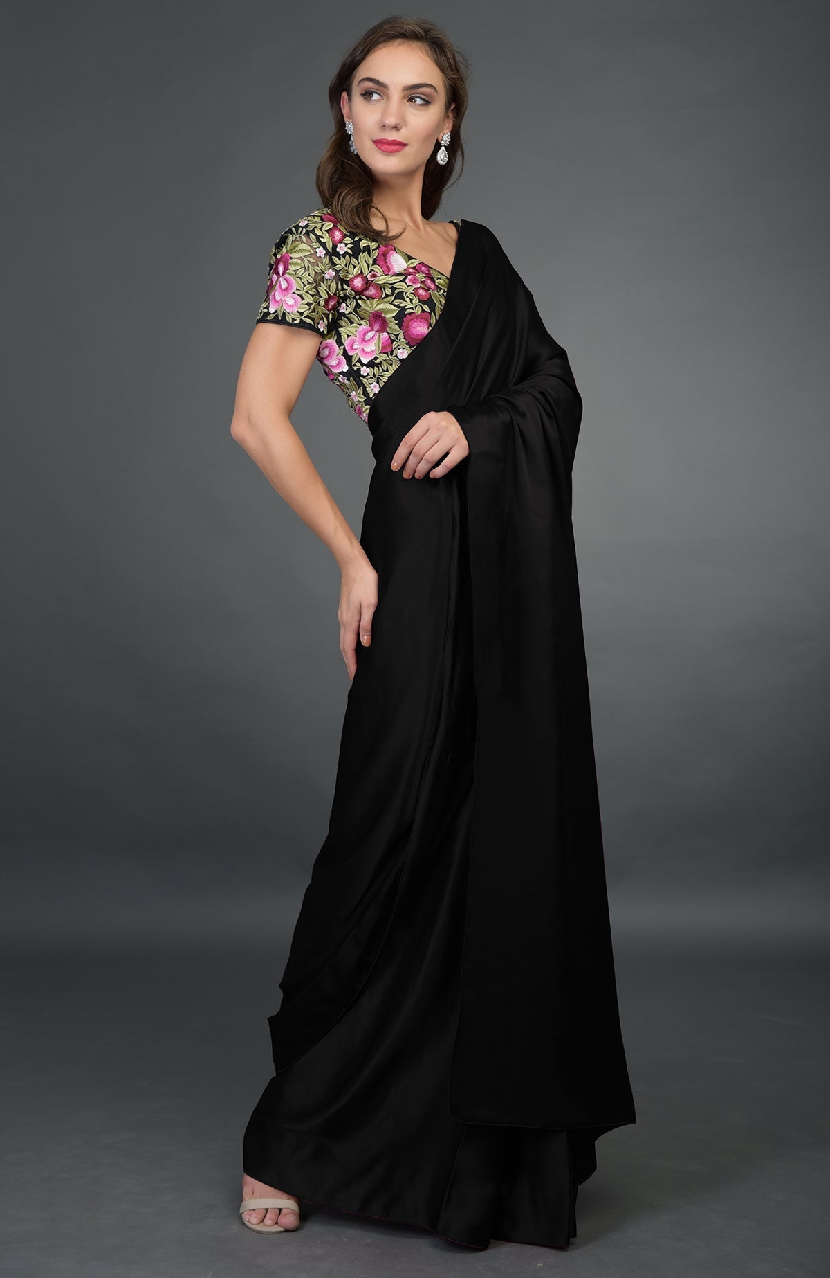 A woman models a black satin silk saree with a floral embroidered blouse.