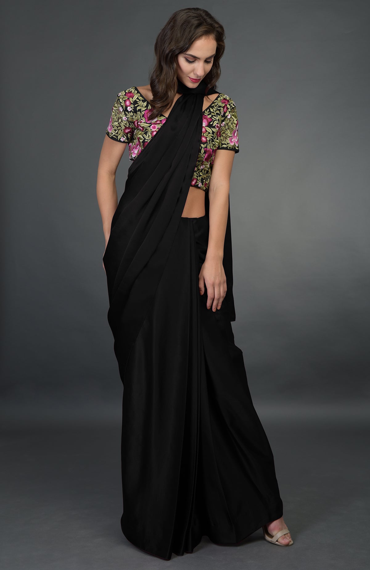 A woman models a black saree with a floral embroidered blouse.