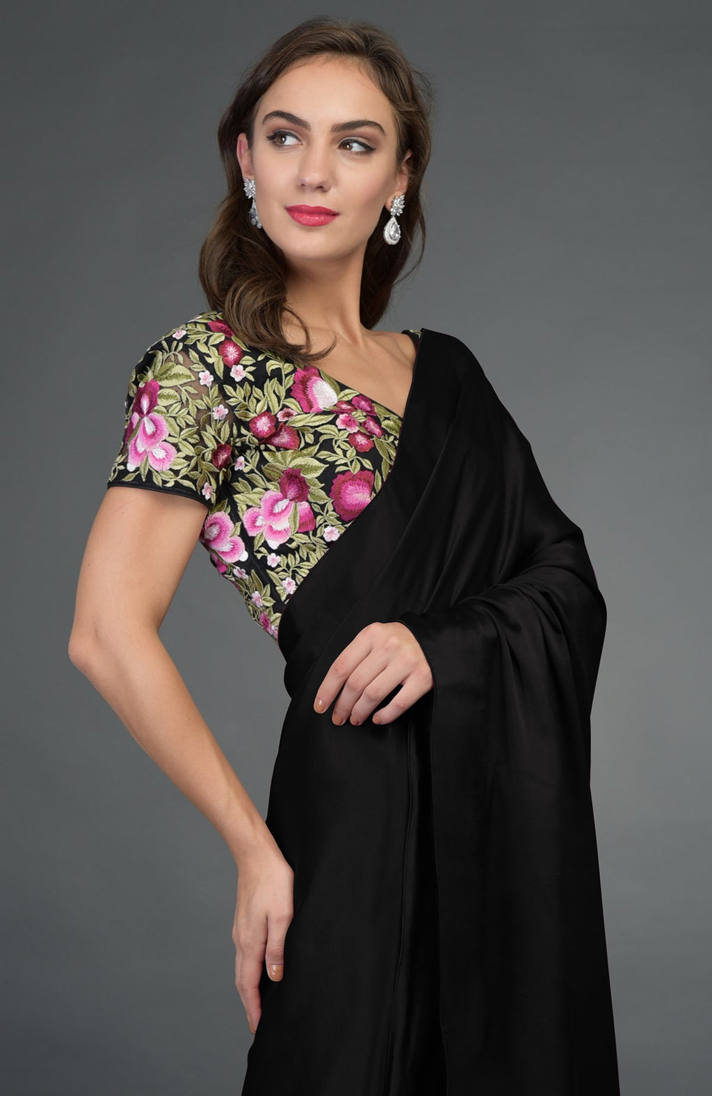 Woman in a black satin silk saree with a floral embroidered blouse.