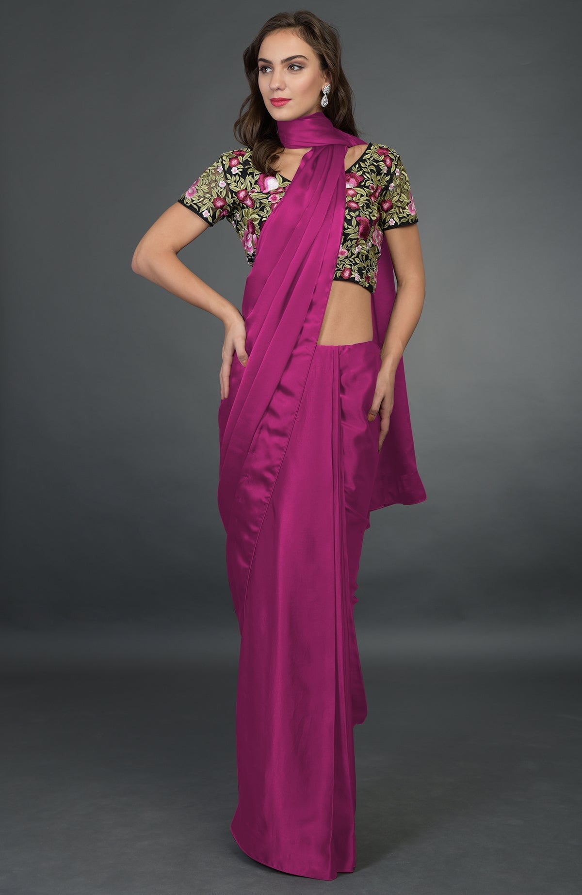 A woman models a raspberry satin silk saree with a floral embroidered blouse.