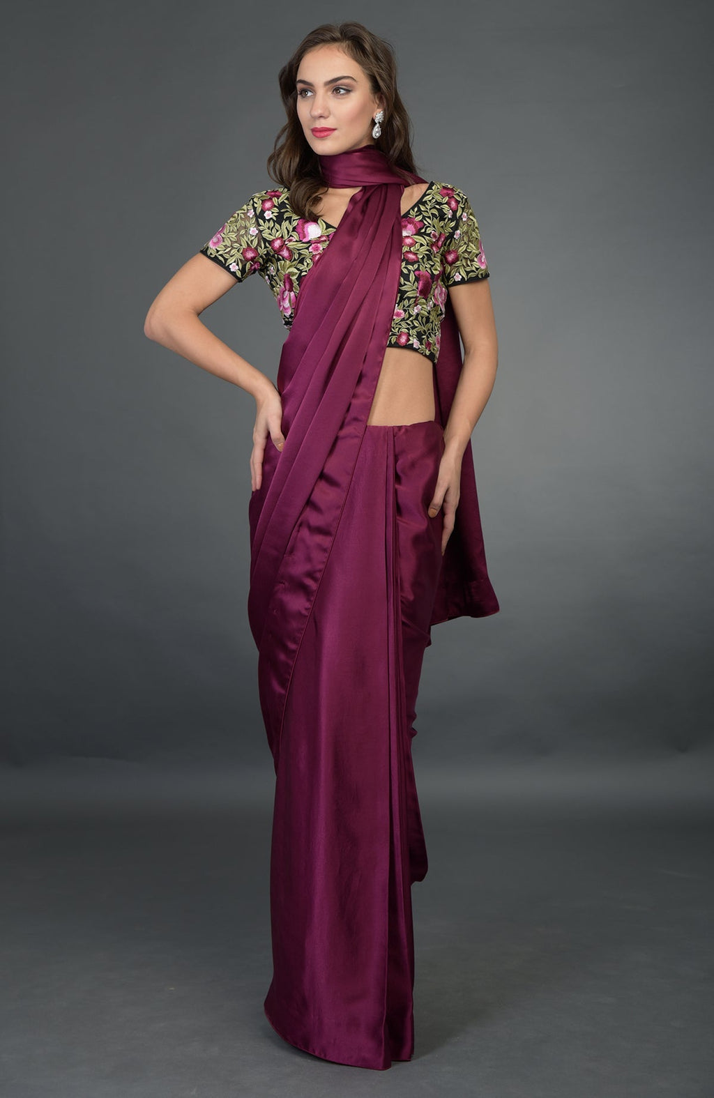 A woman models a plum satin silk saree with a black floral embroidered blouse.