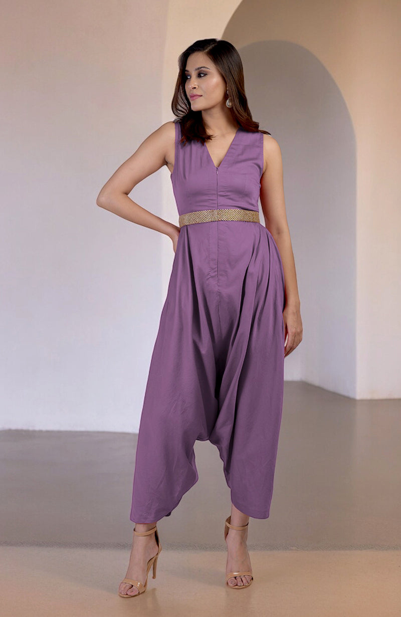 A woman models a purple V-neck jumpsuit with a gold embroidered belt.