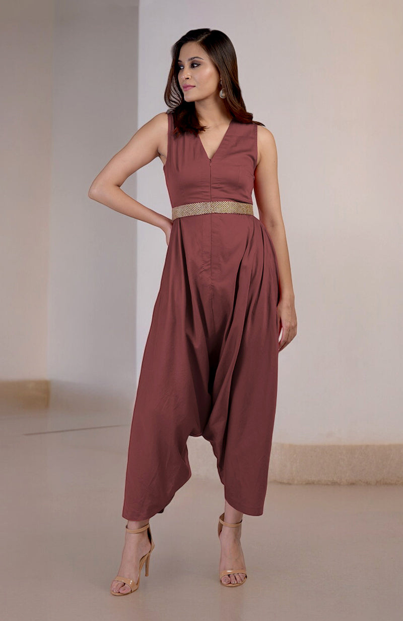 A woman models a V-neck jumpsuit with afgani-style pants and an embroidered belt.