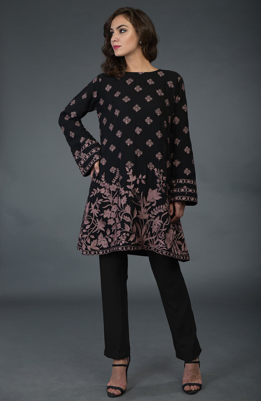 A woman models a black tunic with mauve Parsi embroidery and black pants.