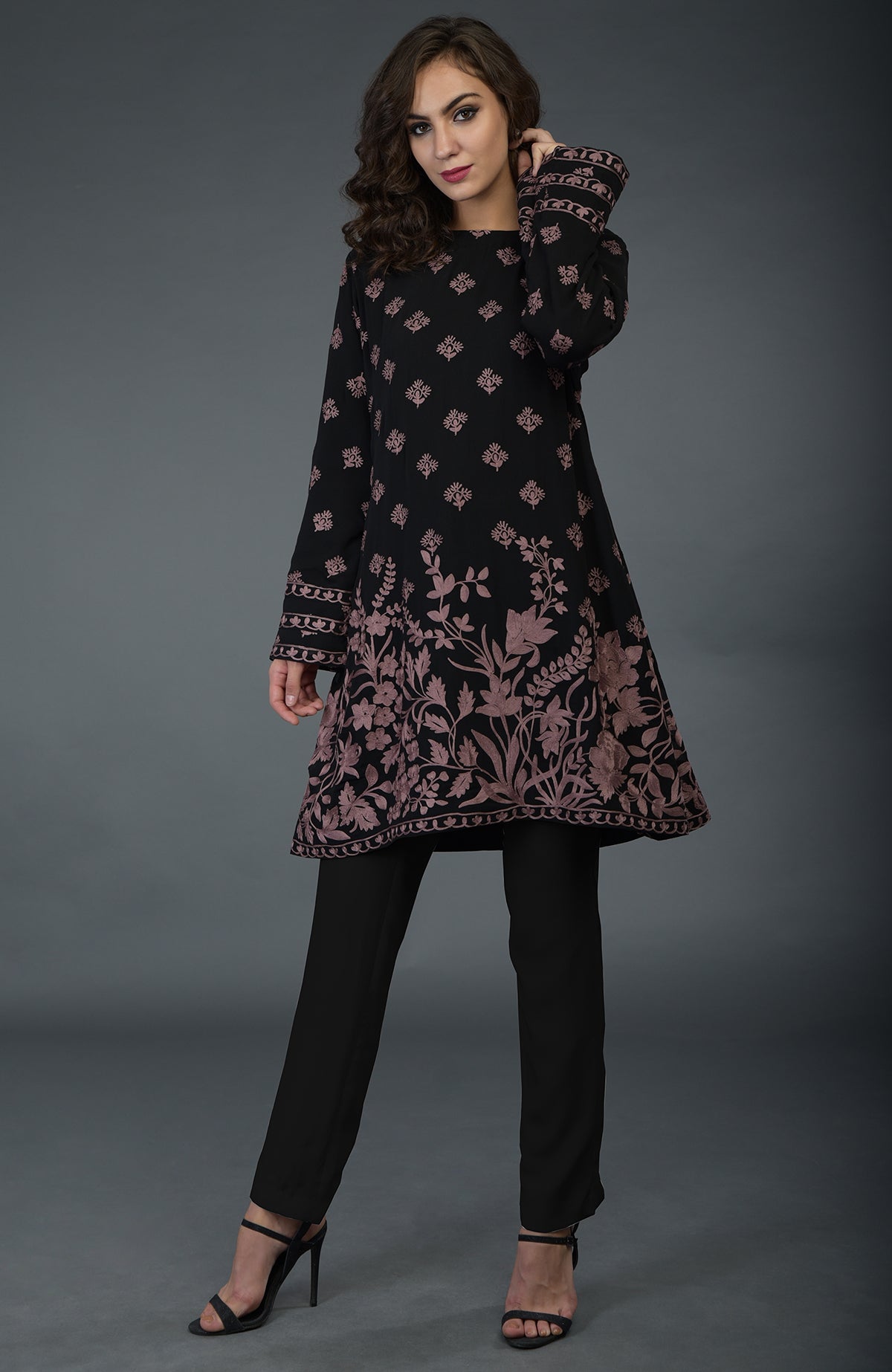 A woman models a black tunic with mauve Parsi embroidery and black pants.