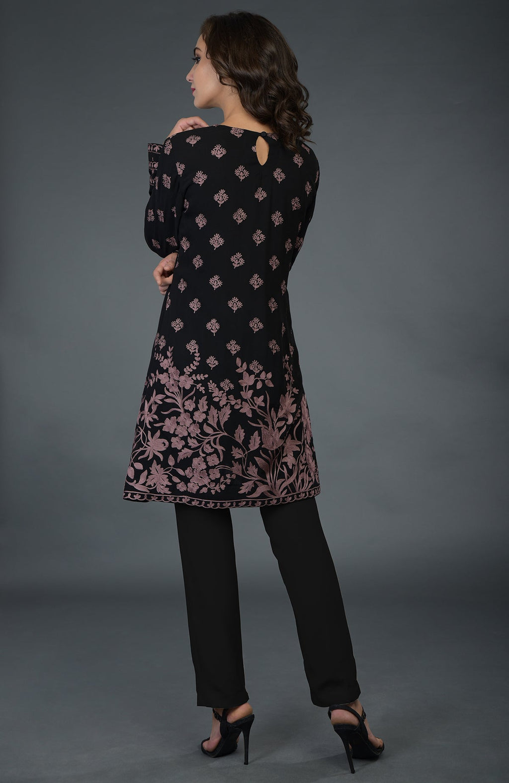 A woman models a black tunic with mauve Parsi embroidery and black pants.