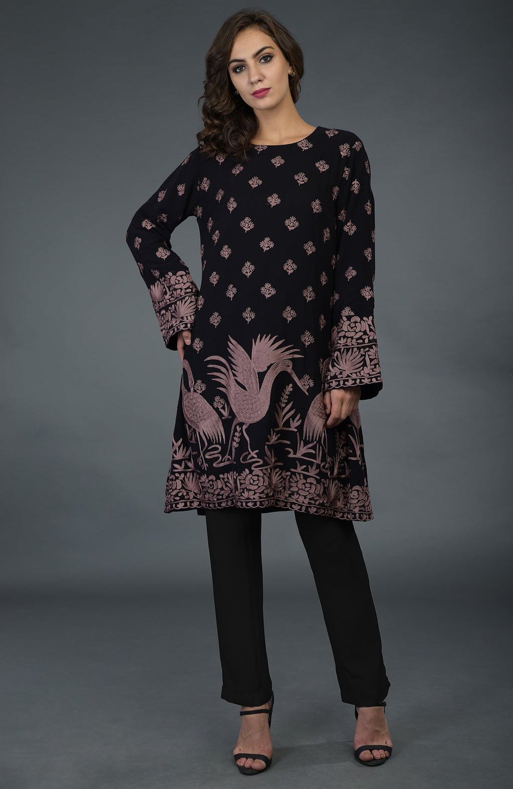 A woman models a black tunic with mauve Parsi embroidery and black pants.