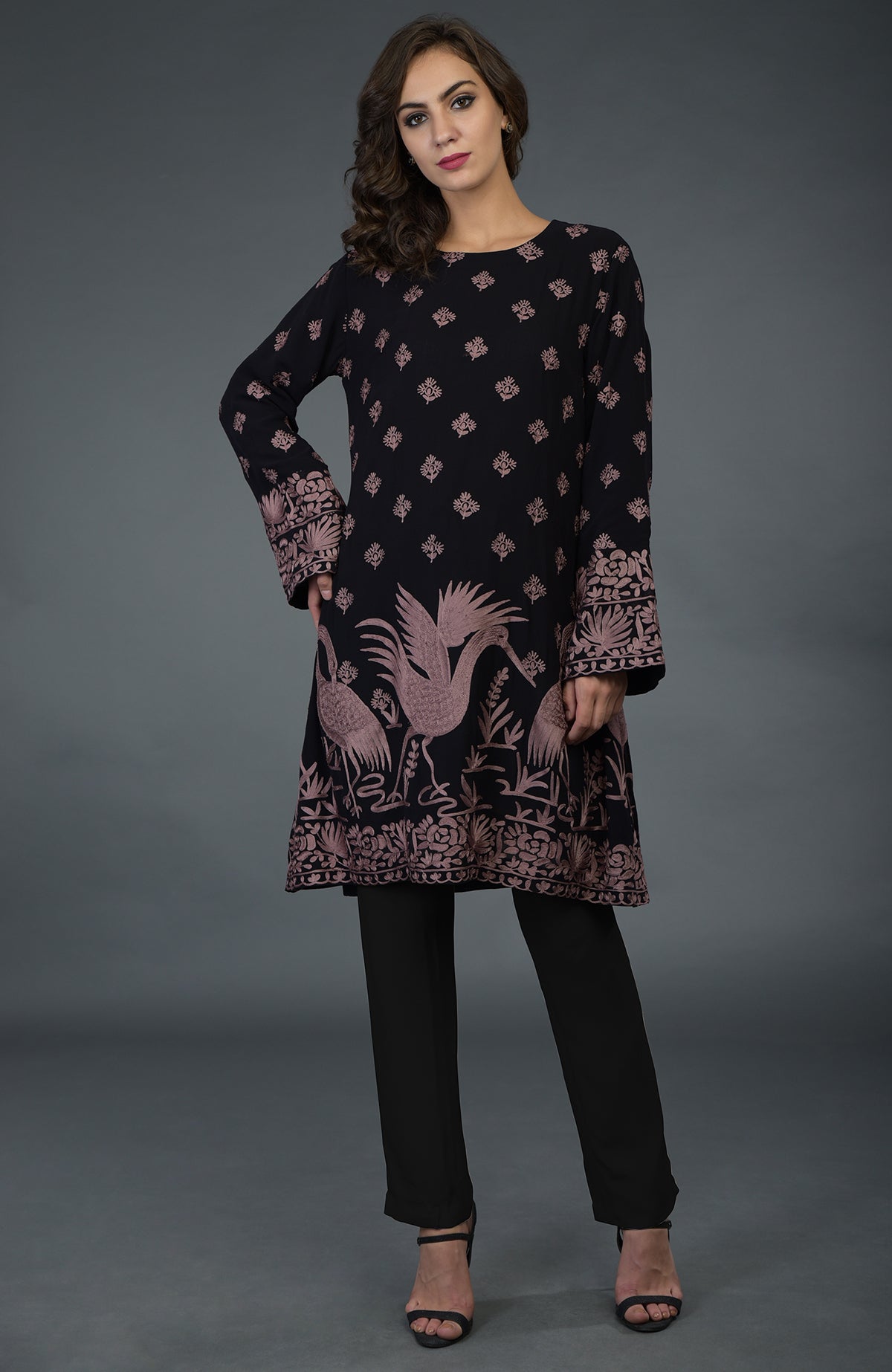 A woman models a black tunic with mauve Parsi embroidery and black pants.
